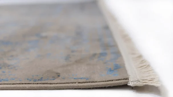 A close-up of a Qaleen Carpets rug's edge, with a focus on the fringe and the carpet's design, showcasing its quality and