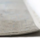 A close-up of a Qaleen Carpets rug's edge, with a focus on the intricate weave and the soft, natural color of the carpet's