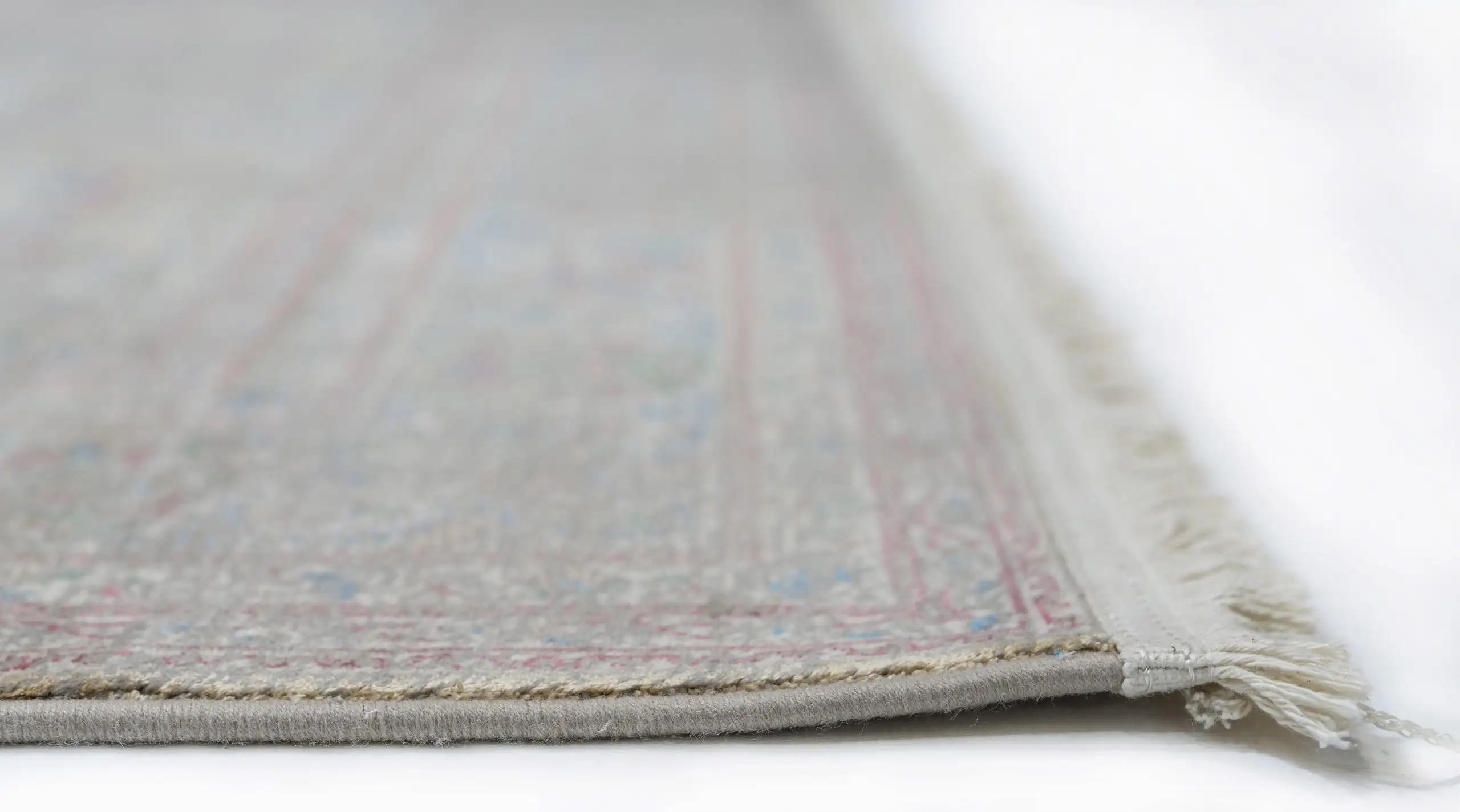 A close-up view of a Qaleen Carpets rug, showcasing its intricate patterns and soft, natural colors