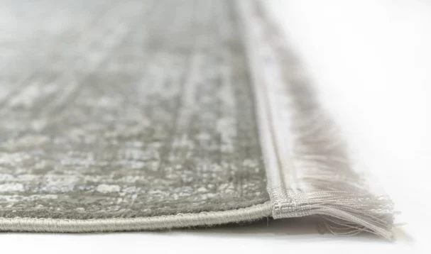 A close-up of a Qaleen Carpets rug's edge, with a focus on its fringe and border
