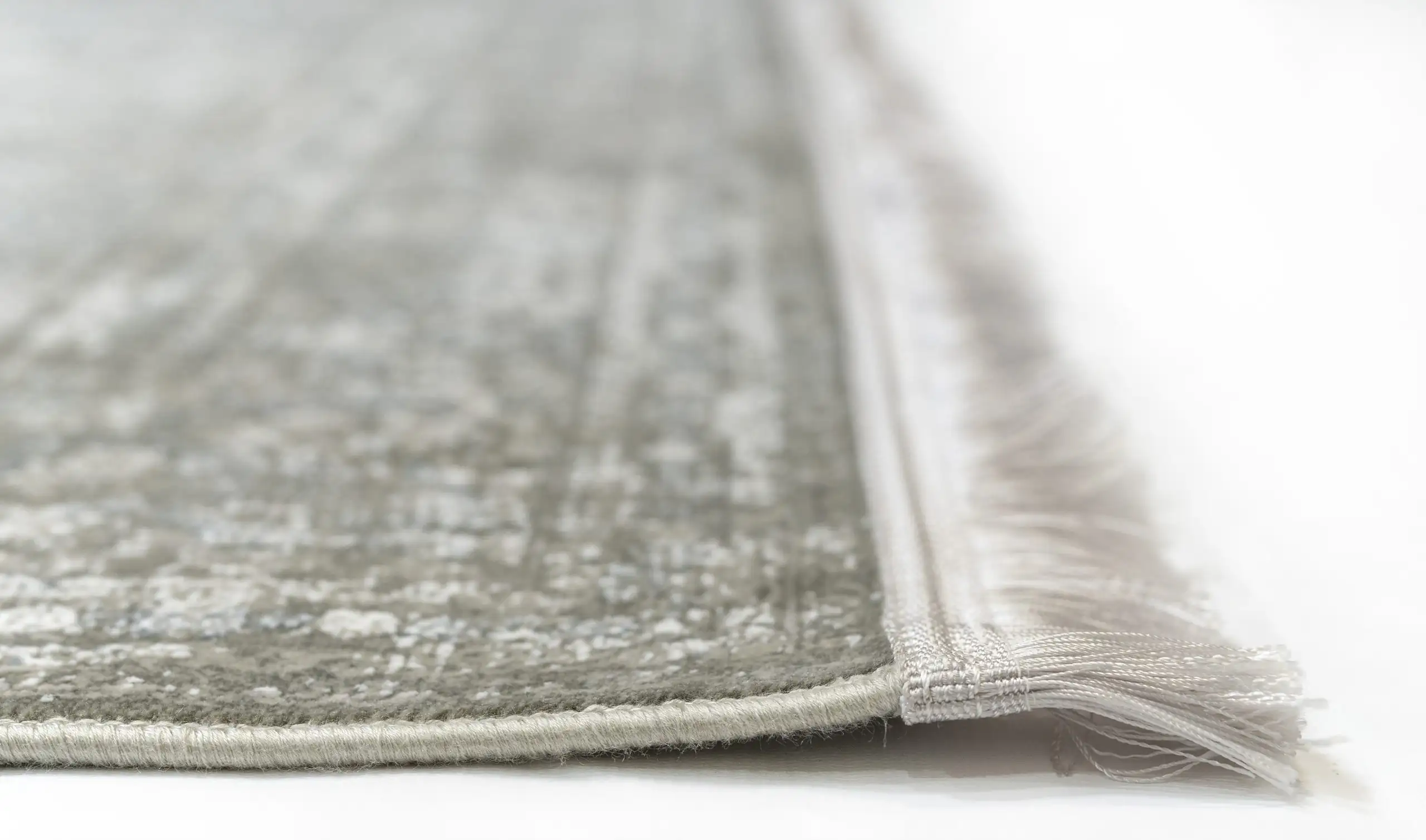 A close-up of a Qaleen Carpets rug's edge, with a focus on its fringe and border