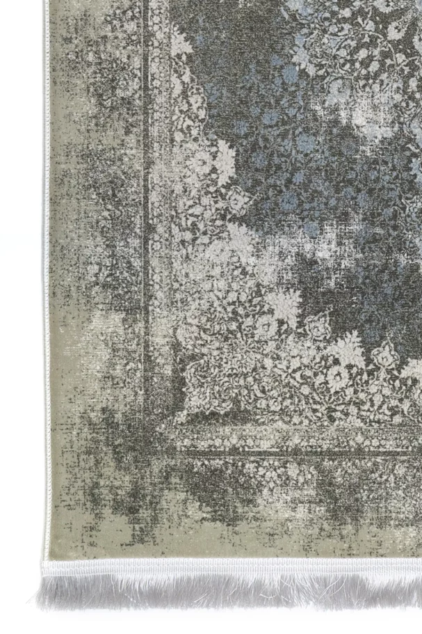 A close-up of a Qaleen Carpets rug with a distressed, vintage-inspired design in muted, earthy tones, featuring a central