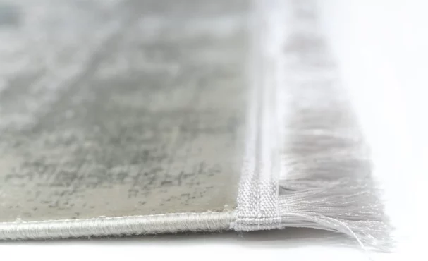 A close-up of a Qaleen Carpets rug's edge, with a focus on its fringe and weaved design