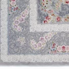 A close-up of a gray rug with a white border and intricate floral patterns, made by Qaleen Carpets
