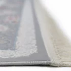 A close-up of a Qaleen Carpets rug with a white border and fringe, featuring a central design in a muted color palette