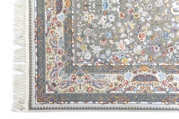 A close-up of a Qaleen Carpets rug with a floral pattern and fringe on a white background