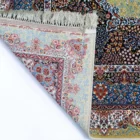 A Qaleen Carpets rug with a mix of patterns and colors, including flowers and leaves, with a fringe at the top and a corner