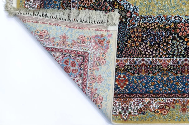 A Qaleen Carpets rug with a mix of patterns and colors, including flowers and leaves, with a fringe at the top and a corner