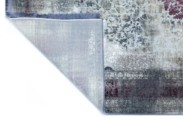 A corner of a rug with a mix of red, white, and grey patterns, with a frayed edge and a subtle sheen, made by Qaleen Carpets