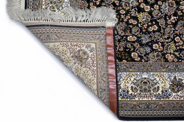 A Qaleen Carpets rug with a black background and intricate floral patterns, partially unrolled to reveal its intricate