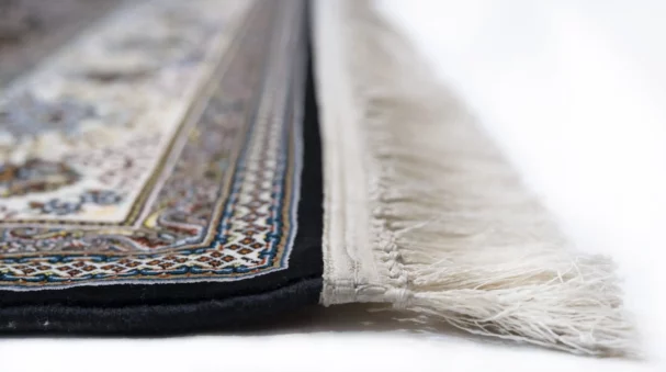 A close-up of a Qaleen Carpets rug with intricate patterns and a fringe, showcasing its high-quality design and craftsmanship