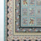 A Qaleen Carpets rug with a floral pattern and intricate design, featuring a mix of blue, green, and gold colors, with a