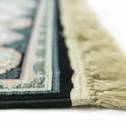 A close-up of a Qaleen Carpets rug with a fringe, featuring a floral pattern and a border, on a white background