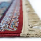 A close-up of a rug's edge, with a red carpet's intricate design and a white border, showcasing the beauty of carpets and