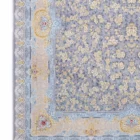 A Qaleen Carpets rug with a light grey background, intricate gold and blue floral patterns, and a fringe at the bottom