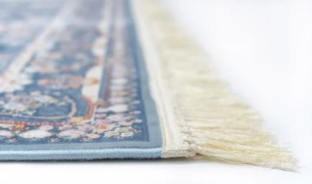 A close-up view of a blue and white rug with a fringe on one edge, showcasing its intricate design and high-quality
