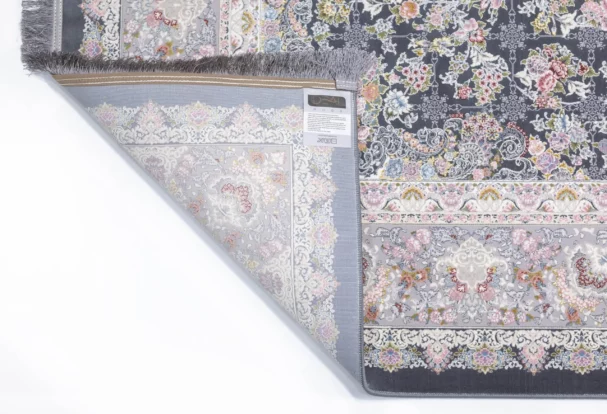 A Qaleen Carpets rug with a floral pattern and fringe, partially unrolled to show the underside and a label with a