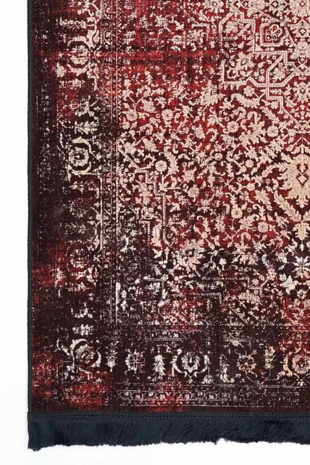 A close-up of a Qaleen Carpets rug with a red and cream pattern, featuring a border and a fringe at the bottom