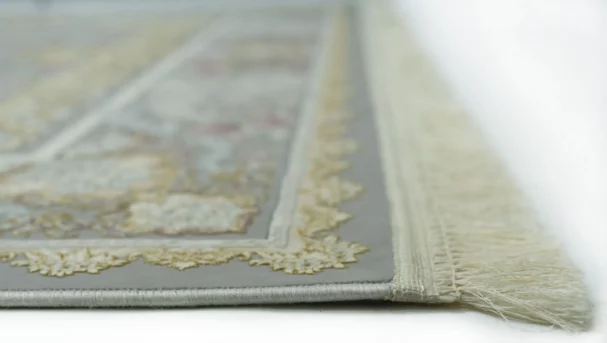 A close-up view of a Qaleen Carpets rug, with its intricate design and frayed edges on a white background