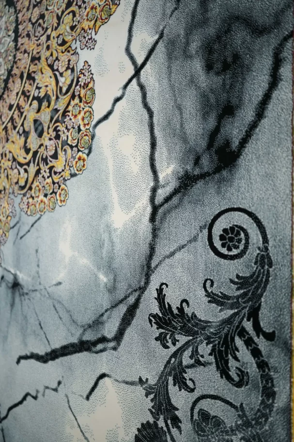 A close-up of a carpet with a floral pattern, featuring a mix of gold and black colors, with a focus on the intricate