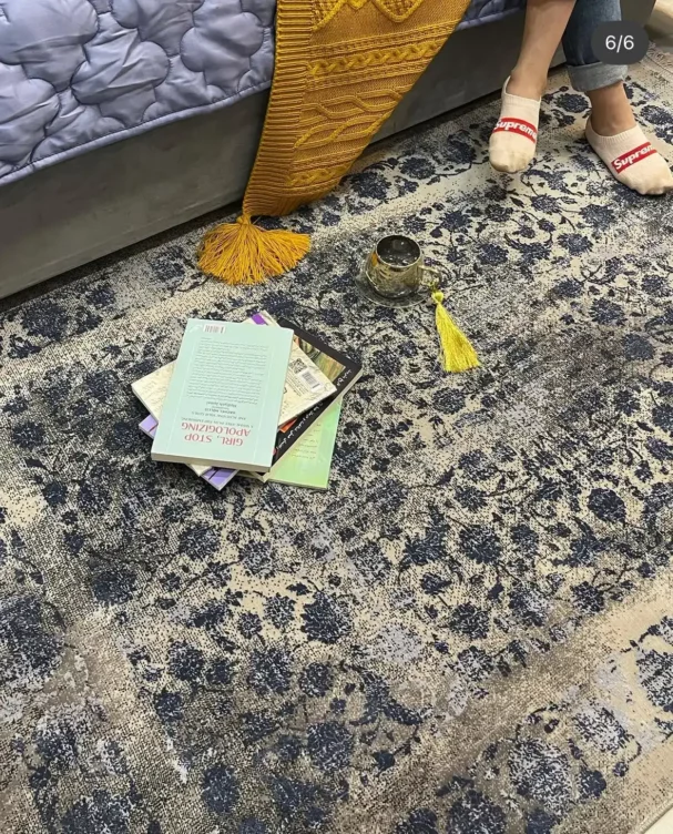 Carpets A person's feet on a rug with a book, a cup, and a rug in the background, with a focus on the rug and the person’s