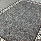 Carpets A beautiful, intricately designed carpet with a grey and white patterned border, laid out on a concrete floor