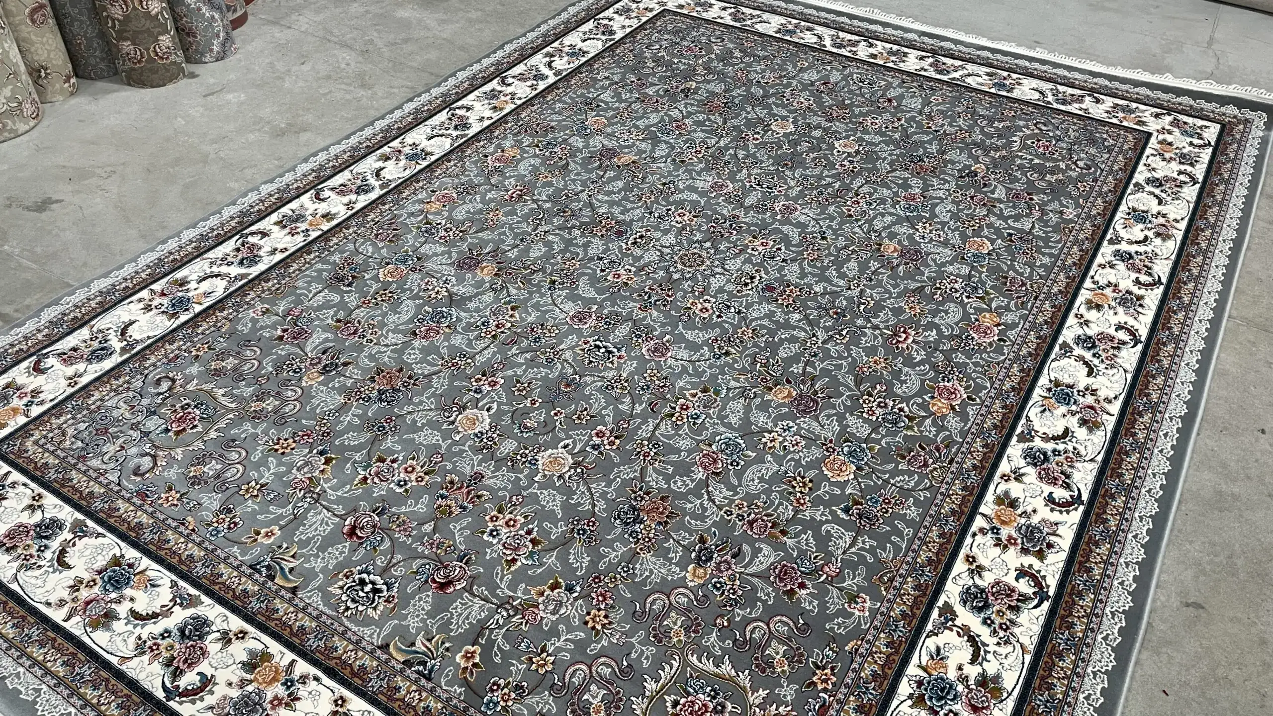 Carpets A beautiful, intricately designed carpet with a grey and white patterned border, laid out on a concrete floor
