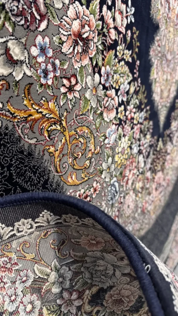 A close-up of a Qaleen Carpets rug with a floral pattern and a dark blue border, showcasing its intricate design and rich