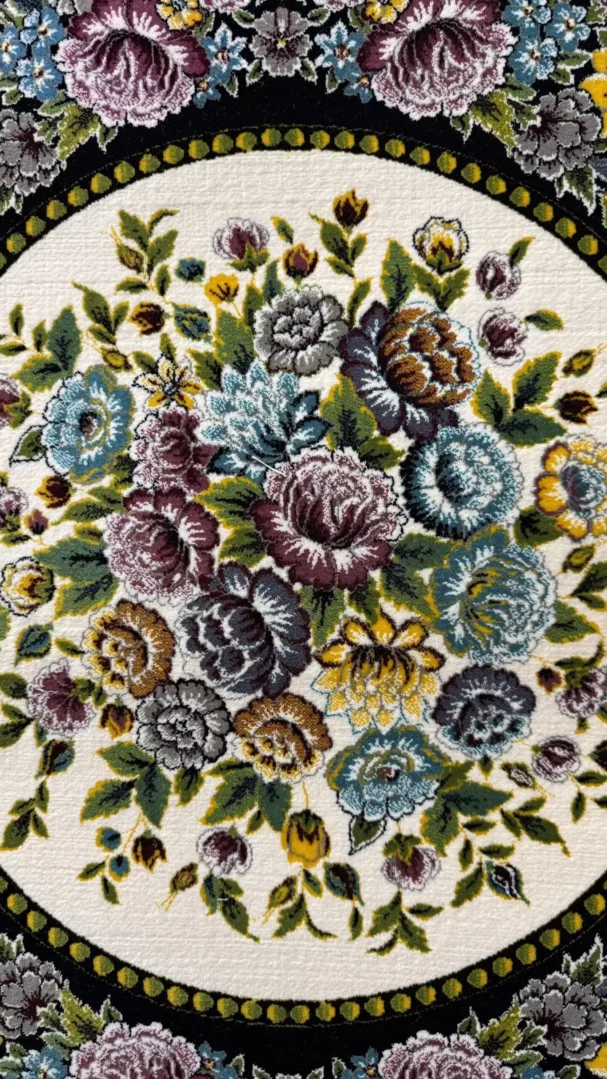 A beautiful, intricately designed carpet with a floral pattern, featuring a mix of colors and a central focus on flowers and